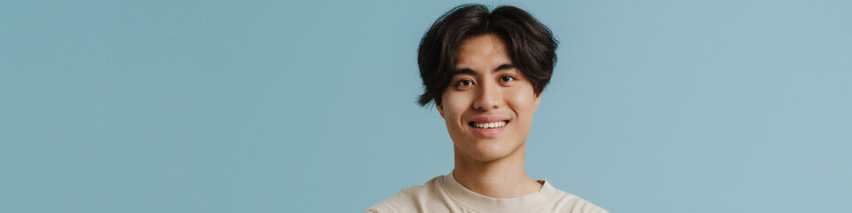 Wall Mural - Young handsome smiling asian boy with folded arms