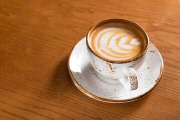 Wall Mural - Hot coffee cup with foam on a wooden table in cafe