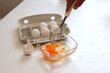 Frau schlägt mit einem Scheebesen rohe Eier zu Rührei