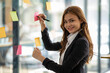 © Wuttichaik - Happy businesswoman planning ideas project work on a glass of wall with colorful memo