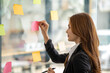 © Wuttichaik - Happy businesswoman planning ideas project work on a glass of wall with colorful memo