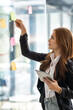 © Wuttichaik - Happy businesswoman planning ideas project work on a glass of wall with colorful memo