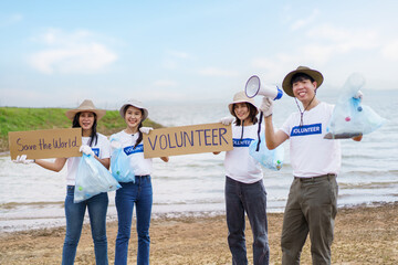 Group of Asian young people volunteer helping to collecting or picking up a plastic bottle garbage on the ground in park.