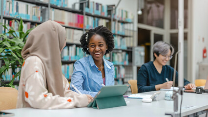 Multiethnic group of students sitting in a library and studying together
