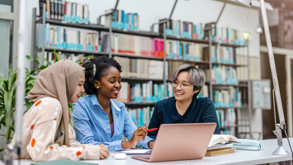 multiethnic group of students sitting in a library and studying together