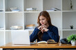 © Wuttichaik - Candid young attractive happy smiling female Student employee studying online learning class video call zoom discord by laptop computer and write on the book chilling at home university
