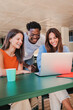 © Jose Calsina - Vertical portrait of a group of multiracial happy teenage students using laptop, working on university homework project in college library. Meeting of young people looking information on computer