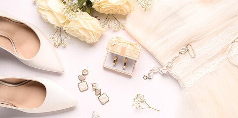 Box with wedding rings, jewelry, female shoes, flowers and dress on white background