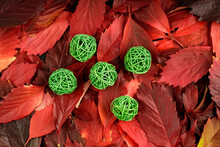 Five Green Woven Balls On The Background Of Autumn Red Leaves