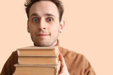 Wall Mural - Young man reading book on beige background, closeup