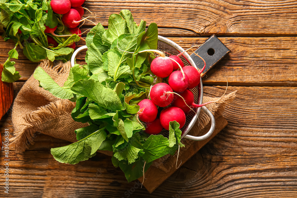 Colander with fresh radish on wooden background