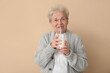 © Pixel-Shot - Senior woman drinking milk on beige background