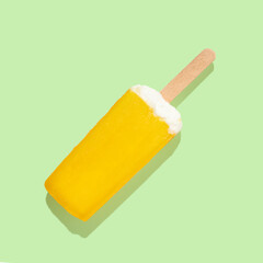 Wall Mural - Orange ice cream on a stick on green pastel background