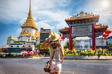 a tourist woman on sightseeing tour stands in front of the chinatown gate at the famous yaowarat roa