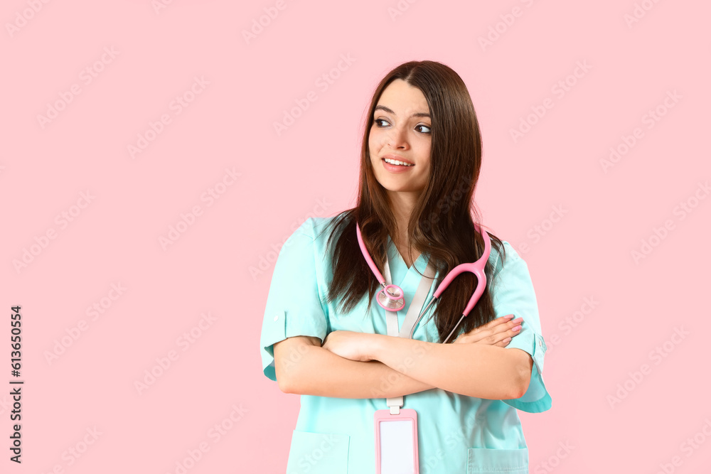 Female medical intern with stethoscope on pink background