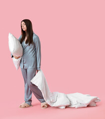 Sticker - Young woman in pajamas with blanket and pillow on pink background