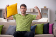 © Elnur - Young man with a lot of pillows sitting on the sofa