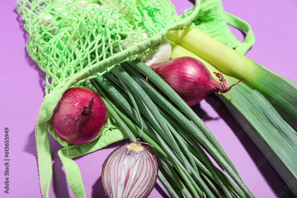String bag with different kinds of onion on purple background, closeup