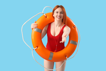 Wall Mural - Female lifeguard with ring buoy on blue background