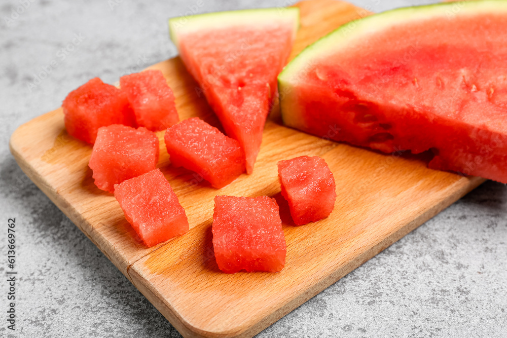 Board with pieces of fresh watermelon on grey background