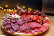 Slices of salami on a wooden board. Assorted charcuterie platter with sliced ham, salami, sausage and spicy chorizo.