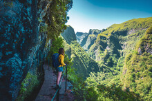 Backpacker Woman Enjoing View From Steep Cliff Jungle Hiking Trail  Next To Canal Through Madeiran Rainforest. Levada Of Caldeirão Verde, Madeira Island, Portugal, Europe.