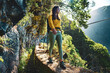 © Michael - Tourist woman walking below big rock wall along water canal through Madeiran rainforest. Levada of Caldeirão Verde, Madeira Island, Portugal, Europe.