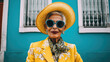 Starsza pani, elegancko ubrana, letni strój, zółty z niebieskimi okularami, w tle niebieski dom