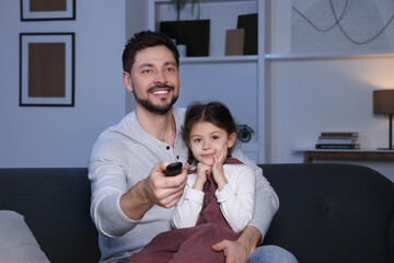 Canvas Print - Father and daughter at home. Happy man changing TV channels with remote control