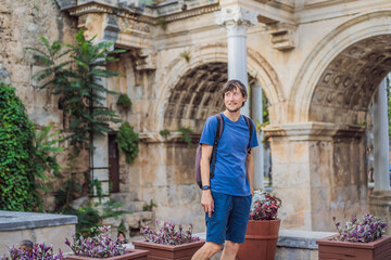 Happy male tourist traveler discover interesting places and popular attractions and walks in the old city of Antalya. Hadrian Kapisi turkey landmark city history. Popular tourist attraction - ancient