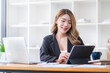 © wattana - Charming Asian female entrepreneur sitting at desk in modern office and using digital tablet.