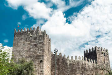 Wall Mural - Guimaraes, Portugal. April 14, 2022: Walls and structures of Guimarães castle with blue sky.