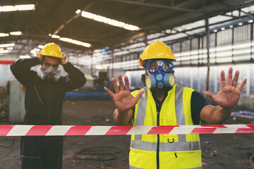 Group of chemical specialist wear safety uniform, gas mask showing hands signal no entry chemical dangerous area in the industry factory while standing behind line area barrier red and white colour