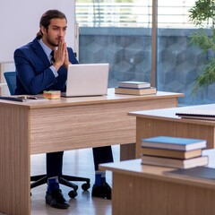 Wall Mural - Young male teacher in suit in the classroom