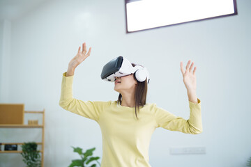 Young Asian woman gamer wearing virtual reality touching air during the VR experience  Future home technology player hobby playful enjoyment concept.