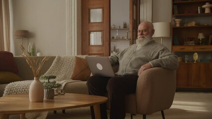 Elderly Man Reading a Message and Laughing Using Laptop