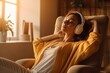 © ttonaorh - Young woman in headphones listening to music at home. Girl sitting on  sofa