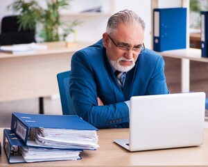 Wall Mural - Old male bookkeeper unhappy with excessive work at workplace