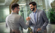 © Bojan - Successful business men in formalwear with hands in a joint handshake gathered into a fist celebrating success at modern glass office.