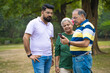 © Niks Ads - Young man showing some detail in smartphone to his father and mother at park