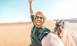 © Davide Angelini - Happy tourist having fun enjoying group camel ride tour in the desert - Travel, life style, vacation activities and adventure concept