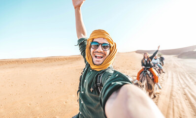 happy tourist having fun enjoying group camel ride tour in the desert - travel, life style, vacation