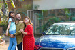© PRASANNAPIX - Happy Indian family standing with new car and watching some on sky.