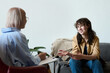 © Mediaphotos - Young smiling woman talking to therapist while she making notes in document during psycho session