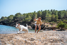 A Man Playing With His Dog On The Beach.