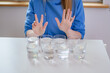 Osiem szklanek wody na stole i dziewczyna w niebieskiej bluzie
