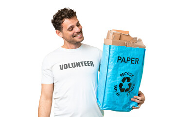 Wall Mural - Brazilian man holding a recycling bag full of paper to recycle over isolated chroma key background with happy expression