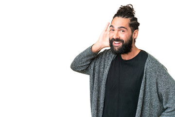 Wall Mural - Young man with beard over isolated chroma key background listening to something by putting hand on the ear