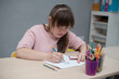 © Ольга Апанасенко - Sunny girl painting in art class at school. World day of people with down syndrome