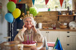 © luckybusiness - Joyful happy lovely senior woman wearing inflatable crown celebrating birthday alone at home, feeling happy.